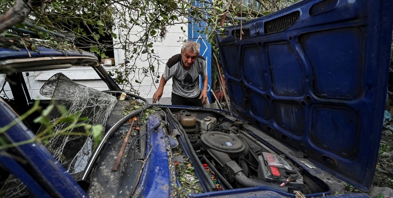 Un hombre se muestra junto a su automóvil, destruido tras el ataque militar ruso. Crédito: Reuters