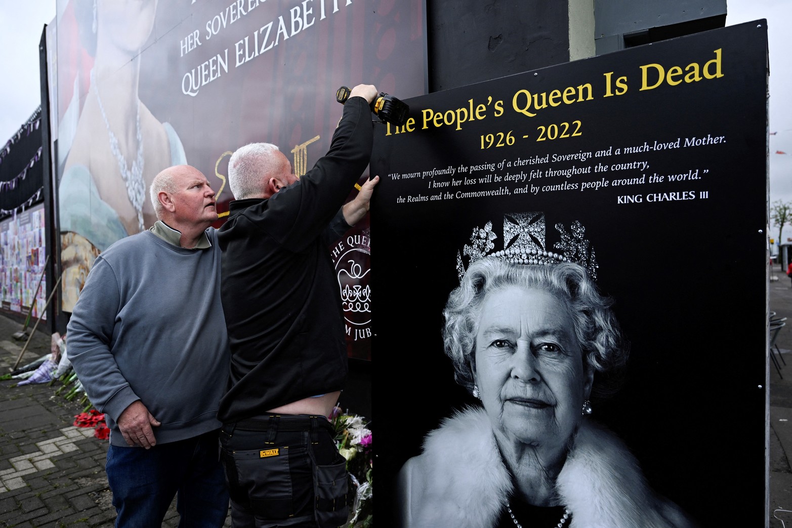 Los hombres instalan un tablero que representa a la reina Isabel de Gran Bretaña, luego de su fallecimiento, en Belfast, Irlanda del Norte. Reuters/Clodagh Kilcoyne