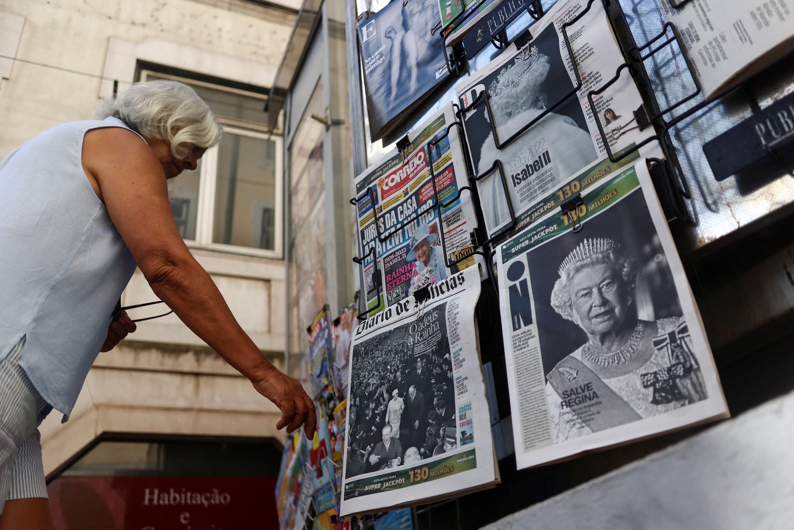 Una mujer se para frente a los periódicos que muestran a la reina Isabel, la monarca británica con el reinado más largo, después de su muerte, en Lisboa, Portugal. Reuters/Pedro Nunes