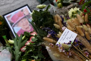 An image of Britain's Queen Elizabeth and floral tributes are seen near a monument, following the queen's passing, in Ballater, near Balmoral, Scotland, Britain, September 10, 2022. REUTERS/Kai Pfaffenbach