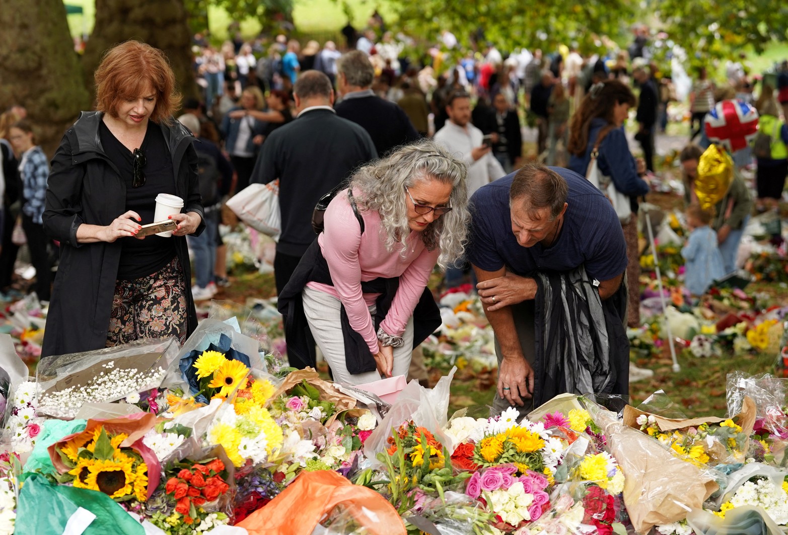 La gente se reúne cerca de los tributos florales colocados fuera del Palacio de Buckingham, tras el fallecimiento de la Reina Isabel de Gran Bretaña. Reuters /Maja Smiejkowska