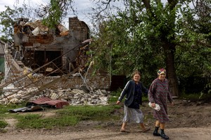 Ukrainian women react as they walk past a destroyed house at a village near a frontline, as Russia’s attack on Ukraine continues, in Mykolaiv region, Ukraine, September 16, 2022. REUTERS/Umit Bektas