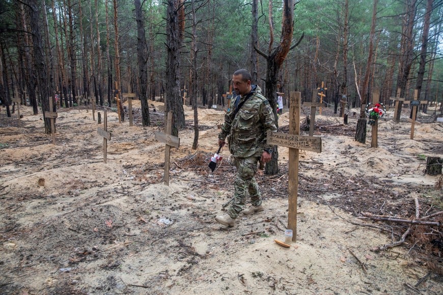 A Ukrainian serviceman walks among graves of mostly unidentified civilians and Ukrainian soldiers at an improvised cemetery in the town of Izium, recently recently liberated by the Ukrainian Armed Forces during a counteroffensive operation, amid Russia's attack on Ukraine, in Kharkiv region, Ukraine September 15, 2022. REUTERS/Oleksandr Khomenko