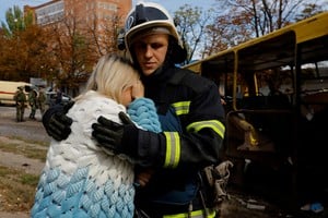 A firefighter comforts a woman next to the destroyed bus in which her daughter was killed by shelling near a local market during Russia-Ukraine conflict in Donetsk, Ukraine September 22, 2022. REUTERS/Alexander Ermochenko