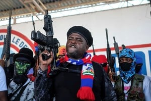 El líder de la banda G9, levanta su arma tras dar un discurso en Puerto Príncipe. Crédito: AP.