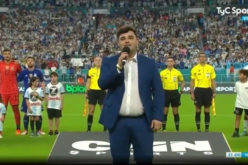 Los Totora: El cantante Juanchi Quieto cantando el Himno Nacional en el partido de la Selección Argentina ante Honduras, delante de Lionel Messi.