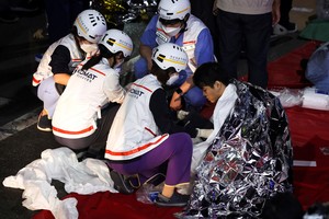 A man receives medical help from rescue team members at the scene where dozens of people were injured in a stampede during a Halloween festival in Seoul, South Korea, October 30, 2022. REUTERS/Kim Hong-ji REFILE - CORRECTING DATE