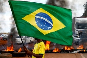 FILE PHOTO: A man holds a Brazilian flag as supporters of Brazil's President Jair Bolsonaro block highway BR-251 during a protest against President-elect Luiz Inacio Lula da Silva who won a third term following the presidential election run-off, in Planaltina, Brazil, October 31, 2022. REUTERS/Diego Vara/File Photo