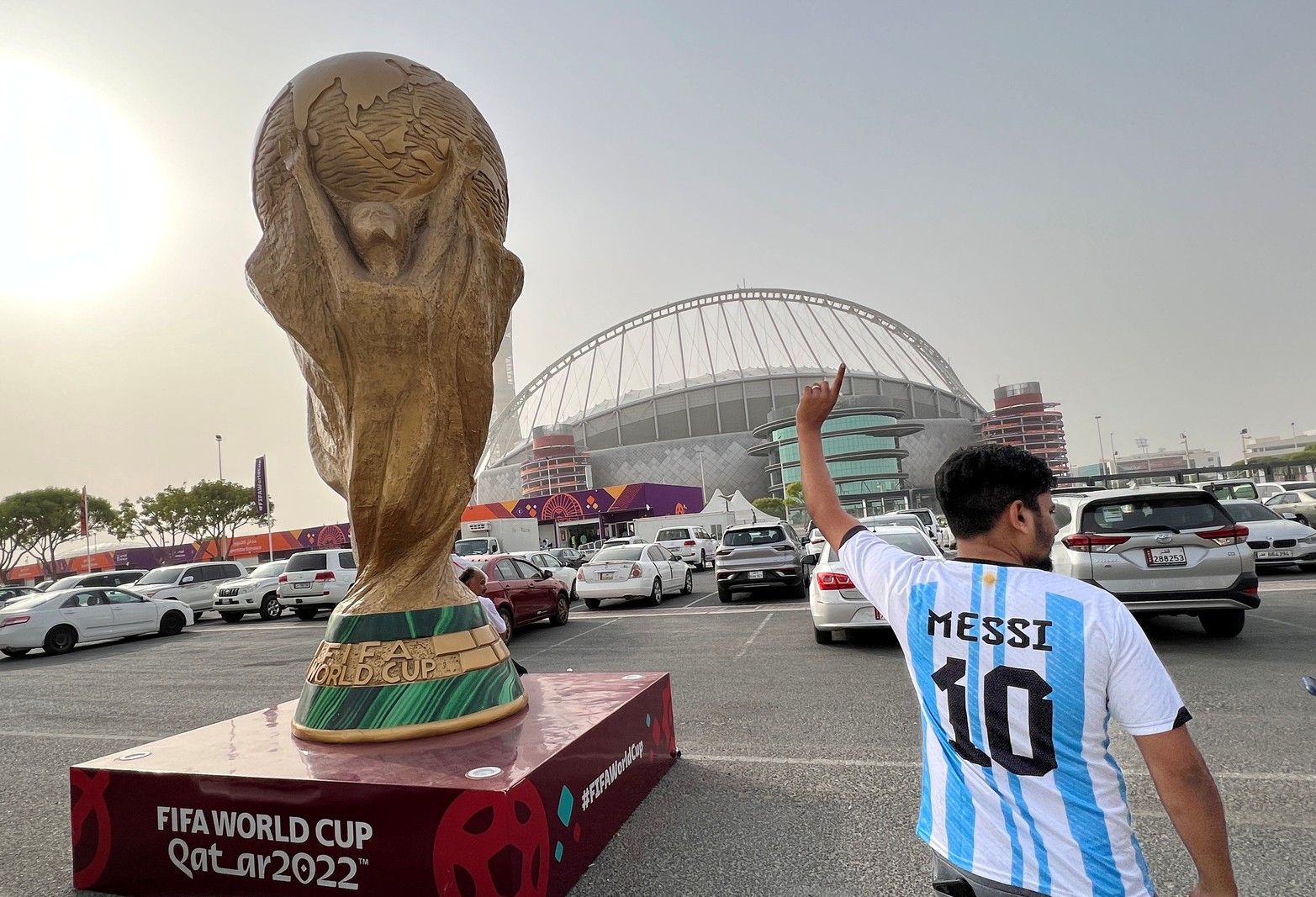 La gente camina junto a una escultura del trofeo de la Copa Mundial frente al Estadio Internacional Khalifa antes del torneo de fútbol de la Copa Mundial FIFA 2022 en Doha, Qatar.