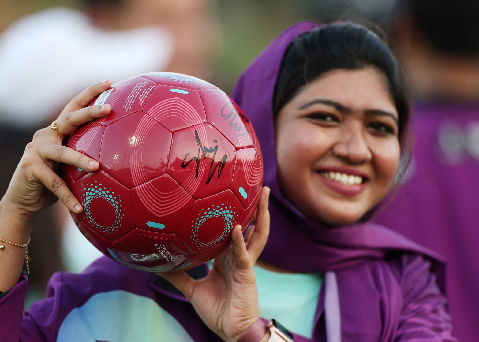 Una voluntaria local posa con un balón de fútbol firmado durante el evento.