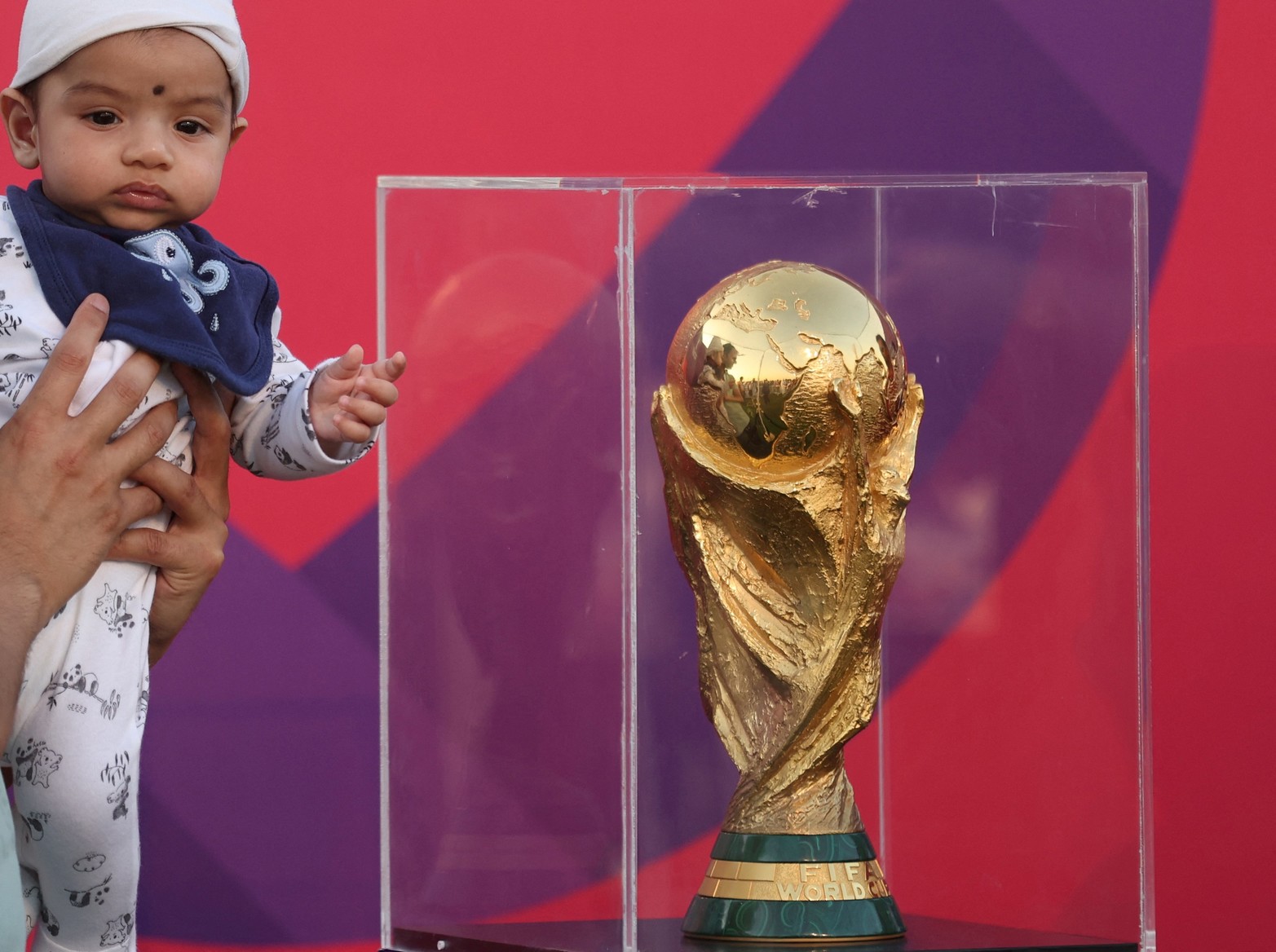 El trofeo de la Copa Mundial se exhibe en Aspire Park - Doha, Qatar. Un bebé mira el trofeo de la Copa Mundial en exhibición durante el evento.