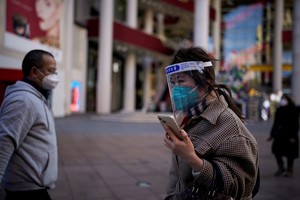 A woman wearing a protective mask and a face shield walks along in a shopping district as China returns to work despite continuing coronavirus disease (COVID-19) outbreaks in Shanghai, China, January 3, 2023. REUTERS/Aly Song