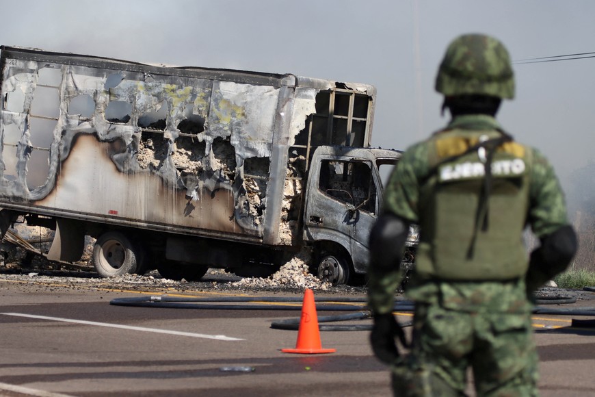 A soldier keeps watch near the wreckage of a burnt vehicle set on fire by members of a drug gang as a barricade, following the detention by Mexican authorities of drug gang leader Ovidio Guzman in Culiacan, a son of incarcerated kingpin Joaquin "El Chapo" Guzman, in Mazatlan, Mexico, January 5, 2023. REUTERS/Stringer NO RESALES. NO ARCHIVES