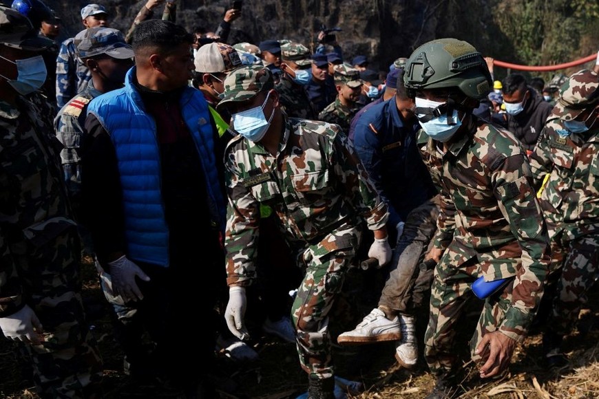 Miembros del Ejército de Nepal llevan el cuerpo de la víctima de un accidente aéreo en el lugar del accidente de un avión que transportaba a 72 personas en Pokhara. Créditos: Rohit Giri/ Reuters