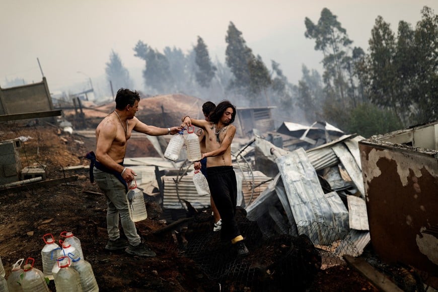 Residents try to extinguish fire as a wildfire burns part of rural areas in Tome, Chile, February 3, 2023. REUTERS/Juan Gonzalez