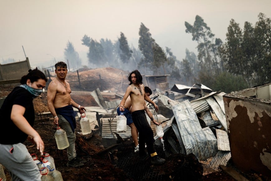 Residents try to extinguish fire as a wildfire burns part of rural areas in Tome, Chile, February 3, 2023. REUTERS/Juan Gonzalez