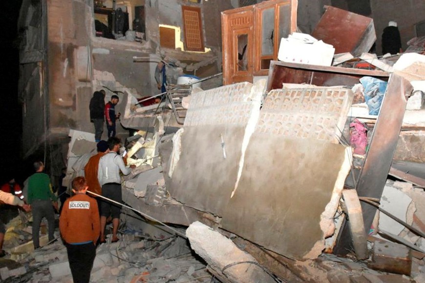 Las personas se reúnen en el sitio de un edificio derrumbado. Céditos: SANA Folleto/ Reuters