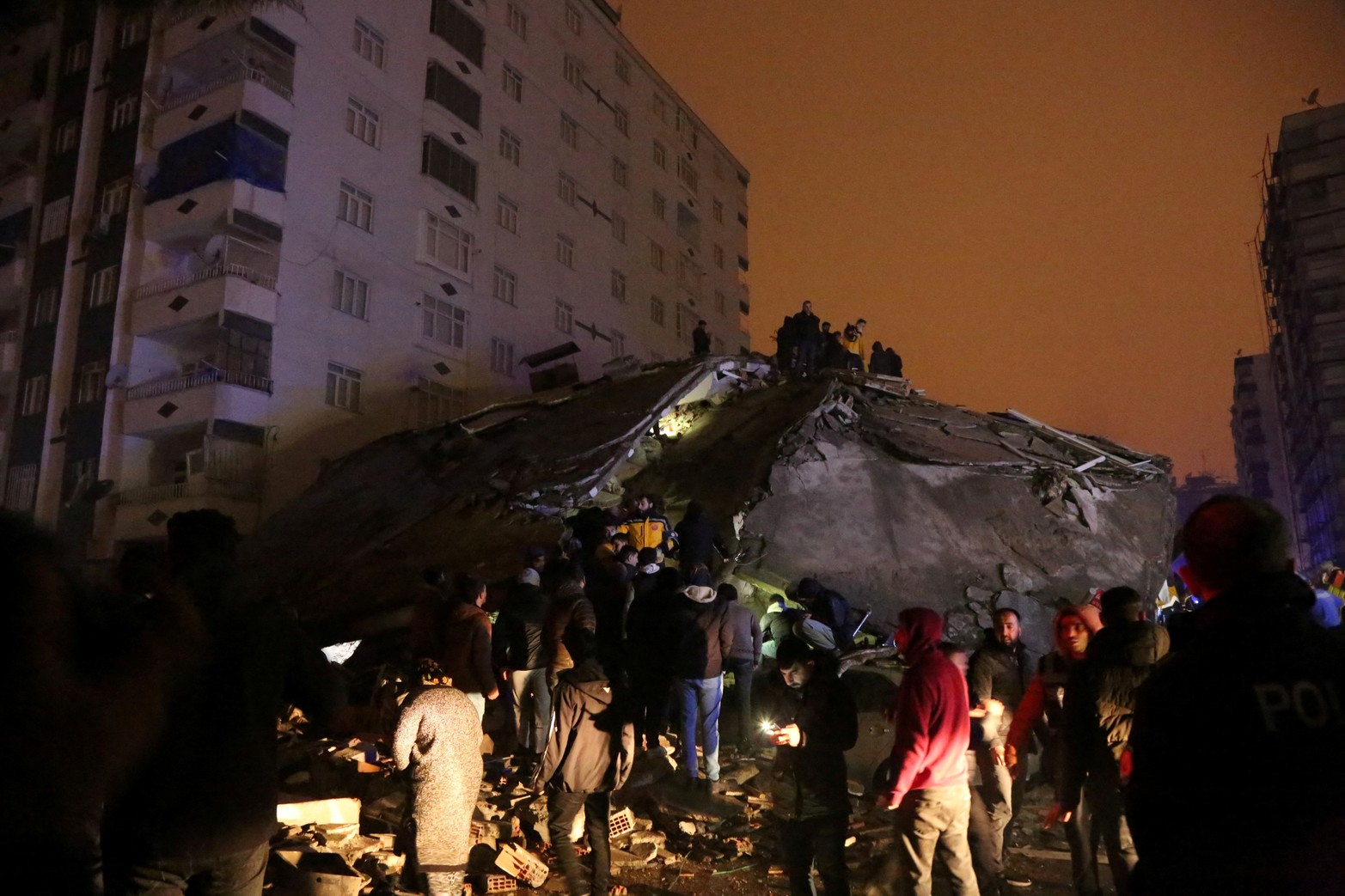 Las personas se reúnen en el sitio de un edificio derrumbado.