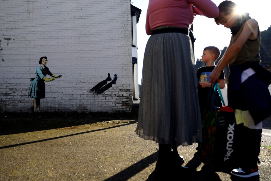 People look at an artwork depicting violence against women, painted by street artist Banksy for the occasion of Valentines Day on a residential street in Margate, Kent, Britain, February 14, 2023. REUTERS/Hannah McKay