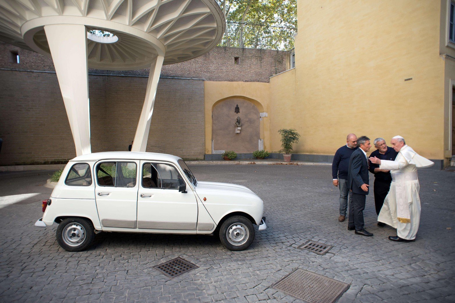 Al Padre Don Renzo Zocca ofreciendo su Renault 4L blanco al Papa Francisco durante una reunión.