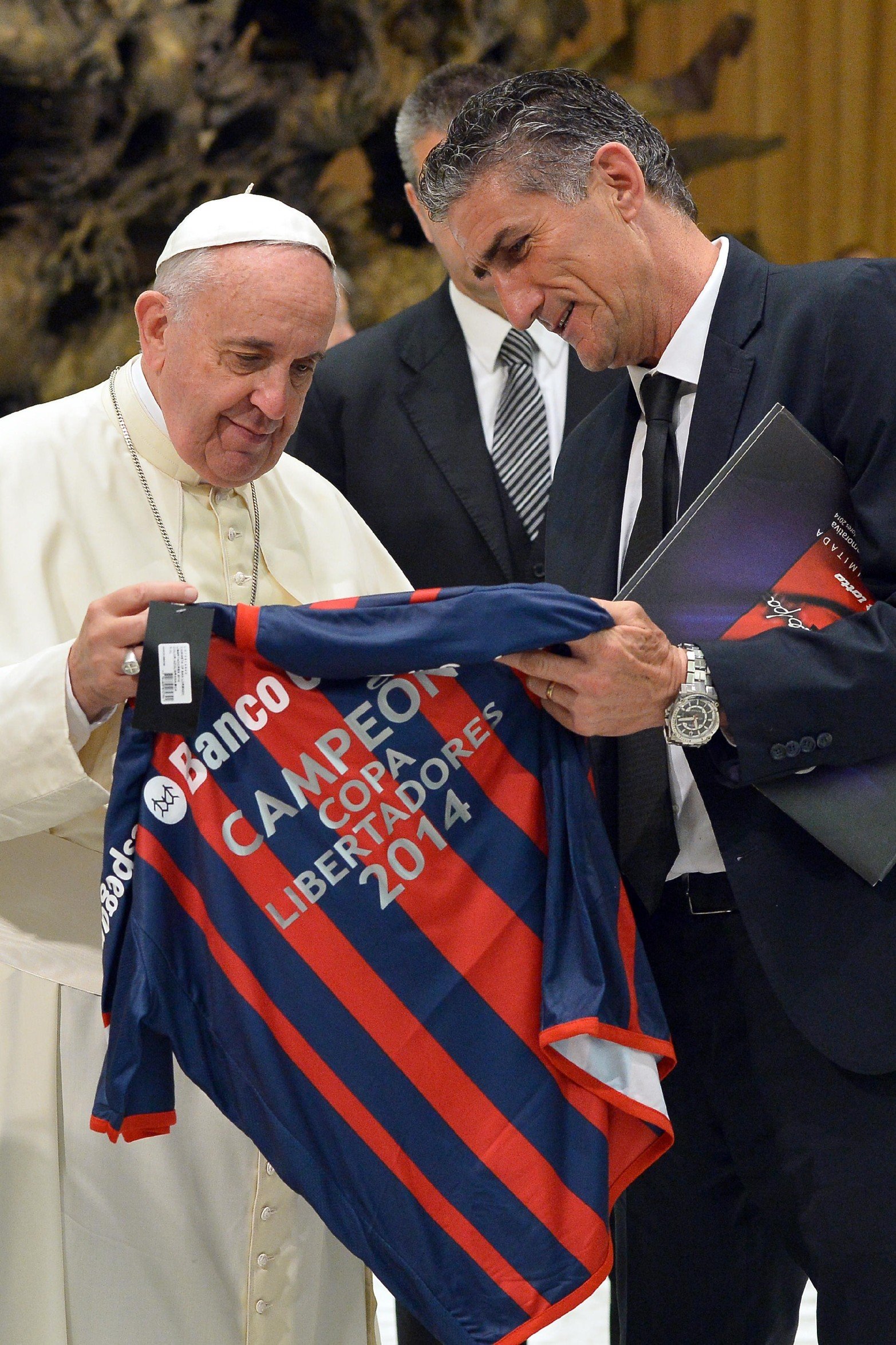 El Papa Francisco recibe una camiseta del equipo de fútbol de San Lorenzo, durante su audiencia semanal el 20 de agosto de 2014 en el Vaticano. El equipo salió Campeón de la Copa Libertadores y era dirigido por Edgardo "Patón" Bauza.