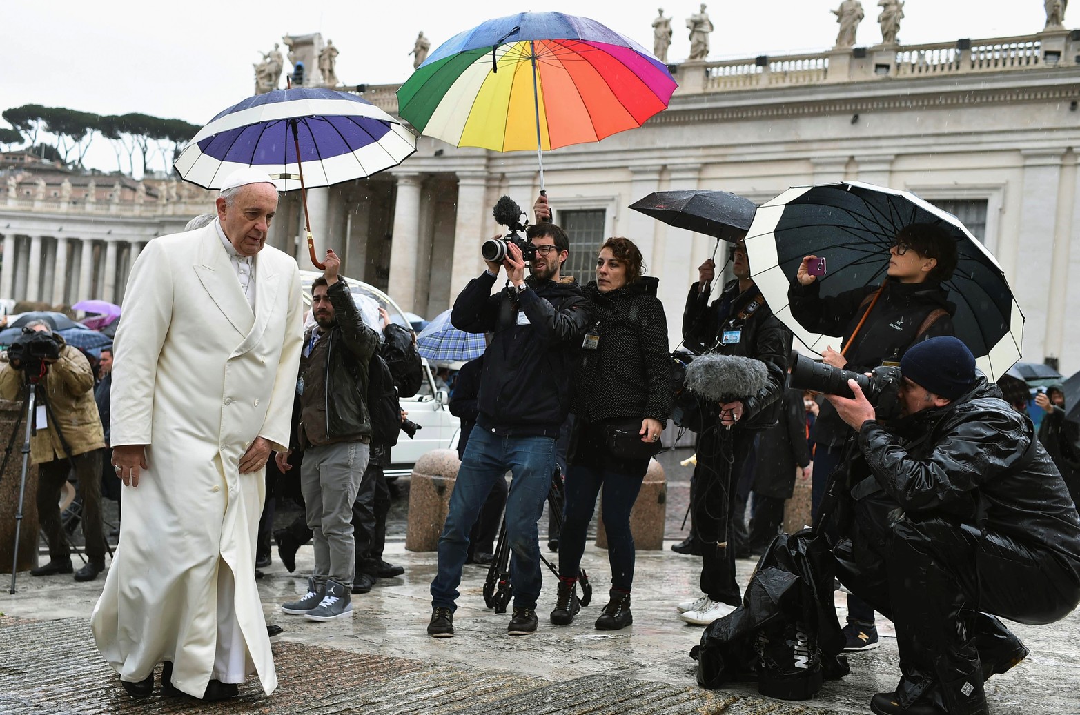 El papa Francisco llega bajo una fuerte lluvia para su audiencia general semanal en la plaza de San Pedro en el Vaticano el 25 de marzo de 2015.