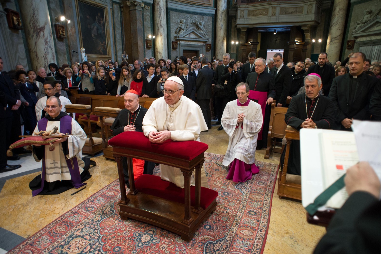 El Papa Francisco rezando en la iglesia de Santa Anna en el Vaticano. Aprovechó el domingo la oportunidad de estrechar la mano de los simpatizantes, sumergiéndose en la multitud que empujaba las barricadas fuera de una puerta del Vaticano mientras los hombres de seguridad y la Guardia Suiza esperaban nerviosos.