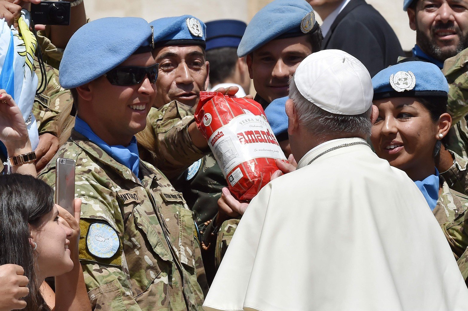 Soldados argentinos de la Fuerza de Paz de las Naciones Unidas en Chipre ofrecen un paquete de hierbas para preparar la bebida tradicional "mate" al Papa Francisco al final de su audiencia general semanal en la plaza de San Pedro el 15 de junio de 2016 en el Vaticano.