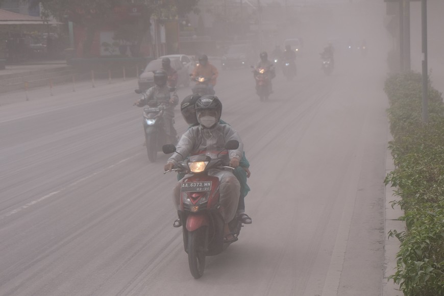 People ride on a road covered by ash from the eruption of Indonesia's Mount MerapiÊvolcano, in Magelang, Central Java province, Indonesia, March 11, 2023. Antara Foto/Anis Efizudin/via REUTERS ATTENTION EDITORS - THIS IMAGE HAS BEEN SUPPLIED BY A THIRD PARTY. MANDATORY CREDIT. INDONESIA OUT. NO COMMERCIAL OR EDITORIAL SALES IN INDONESIA.