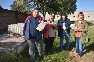 Vecinos de Santa Rita -Luis Pinto, Alicia Borda y Sandra Torea-, y la representante legal de la escuela, Silvia Schonhals, muestran el material de pavimento articulado que compraron hace tres años y que solo falta colocar en la calle. Crédito: Flavio Raina
