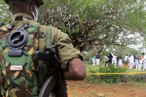 Oficiales de policía montan guardia mientras expertos forenses exhuman los cuerpos. Crédito: REUTERS.