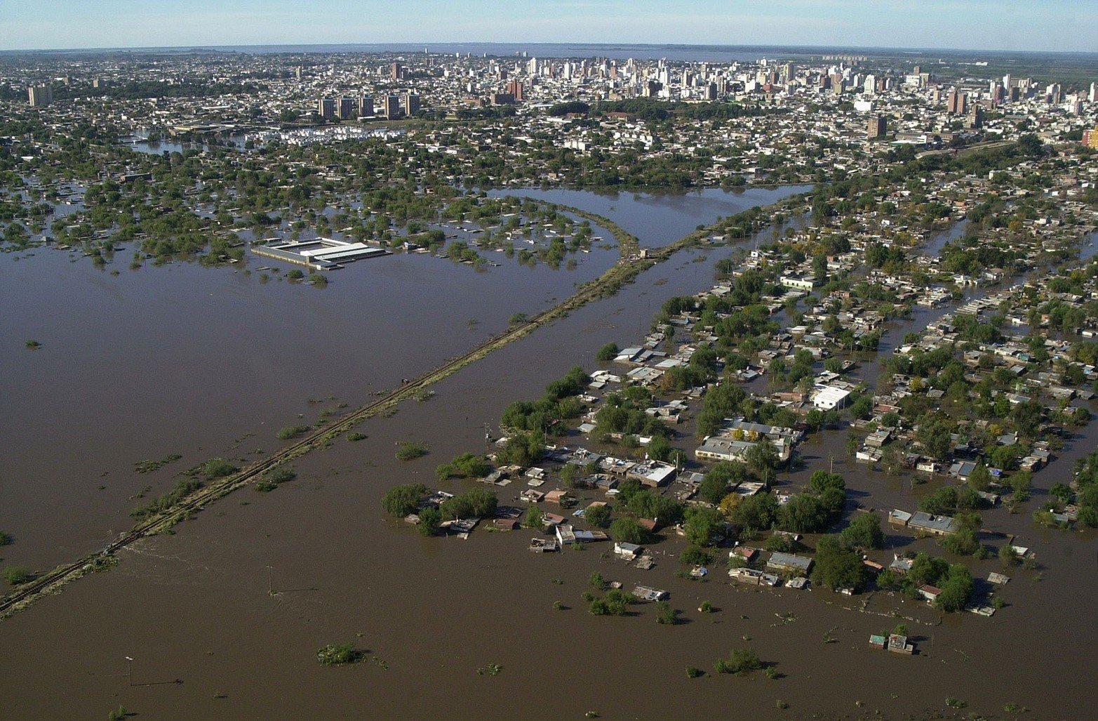 La vía del ferrocarril Mitre divide a la izquierda parte del techo de la escuela Nº 1298 Monseñor Vicente Zaspe. A la derecha barrio Arenales.