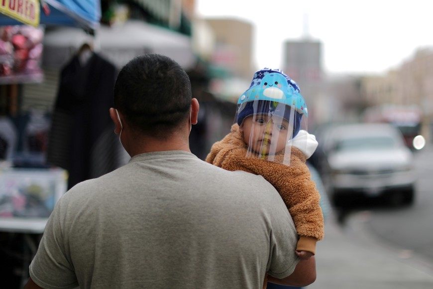 A man carries a baby wearing a mask to protect against the coronavirus disease (COVID-19), in Los Angeles, California, U.S., February 10, 2021. REUTERS/Lucy Nicholson     TPX IMAGES OF THE DAY