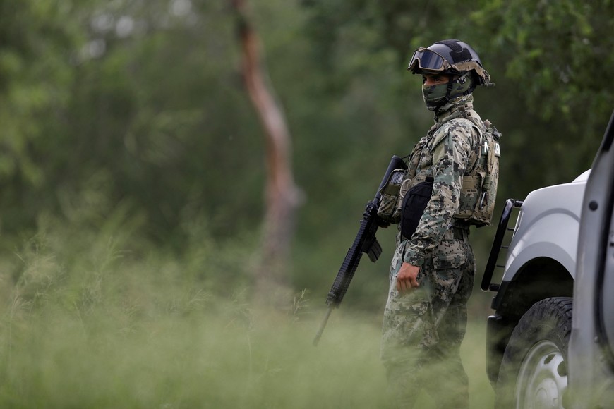 A member of the Mexican Navy stands guard near the banks of the Rio Bravo river as migrants cross the border to turn themselves in to U.S. Border Patrol agents before the lifting of Title 42, in Matamoros, Mexico May 11, 2023. REUTERS/Daniel Becerril
