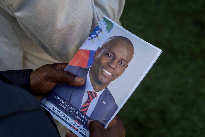 Una persona sostiene una foto del difunto presidente haitiano, quien fue asesinado a tiros en 2021.