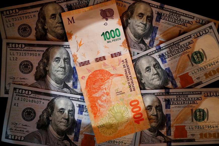 A one thousand Argentine peso bill sits on top of several one hundred U.S. dollar bills in this illustration picture taken October 17, 2022. REUTERS/Agustin Marcarian/Illustration

pesos dolares