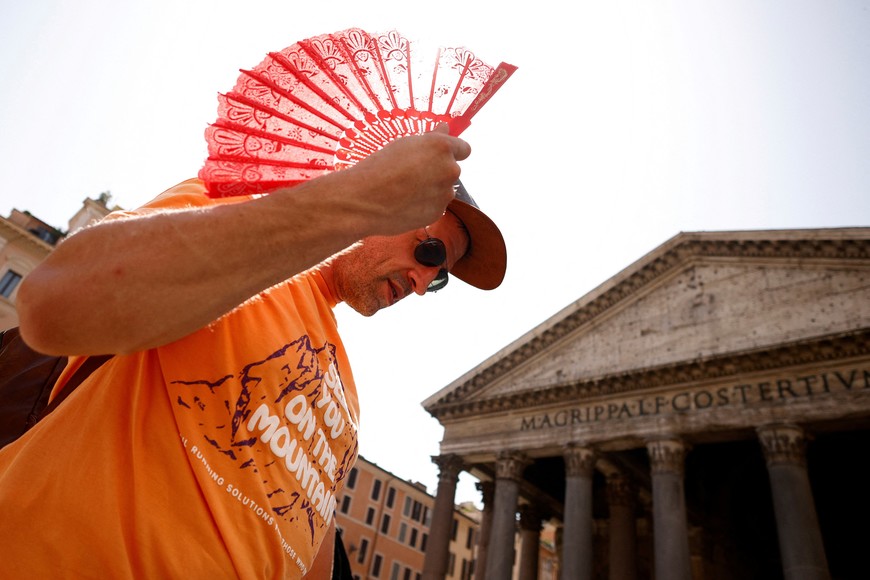 Florian Eberharter from Germany uses a fan to cool off as he queues to enter the Pantheon, during a heatwave across Italy as temperatures are expected to cool off in the Italian capital, in Rome, Italy July 19, 2023. REUTERS/Guglielmo Mangiapane