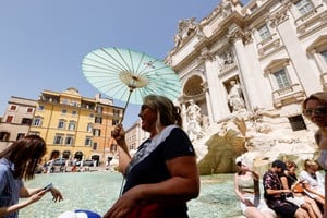 A person holds an umbrella as she takes shelter from the sun near Trevi Fountain during a heatwave across Italy as temperatures are expected to cool off in Rome, Italy, July 20, 2023. REUTERS/Remo Casilli
