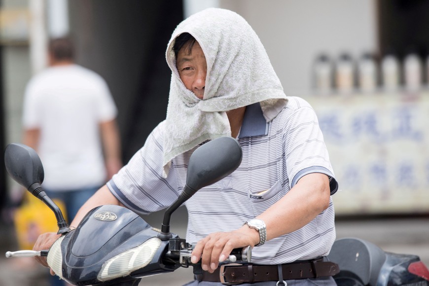FILE PHOTO: A man is seen with a towel tied around his head to escape hot weather as a heat wave hits Hangzhou, Zhejiang province, China, July 10, 2017. Picture taken July 10, 2017. REUTERS/Stringer ATTENTION EDITORS - THIS IMAGE WAS PROVIDED BY A THIRD PARTY. CHINA OUT. NO COMMERCIAL OR EDITORIAL SALES IN CHINA./File Photo