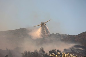 A firefighting plane makes a water drop as a wildfire burns near the village of Vati, on the island of Rhodes, Greece, July 25, 2023. REUTERS/Nicolas Economou