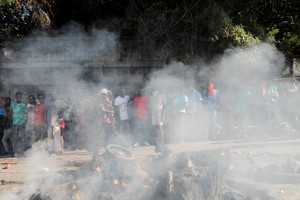 SENSITIVE MATERIAL. THIS IMAGE MAY OFFEND OR DISTURB People stand near the remains of alleged gang members after they were set on fire by a crowd of people, when trying to drive away, in Port-au-Prince, Haiti April 24, 2023. REUTERS/Ralph Tedy Erol