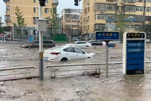 Automóviles parcialmente sumergidos mientras el agua brota en una calle inundada, después de que el tifón Doksuri tocara tierra en China.