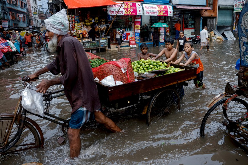 Children push a vegetable seller's cart as streets are flooded amid heavy rains in Dhaka, Bangladesh, June 12, 2023. REUTERS/Mohammad Ponir Hossain     TPX IMAGES OF THE DAY