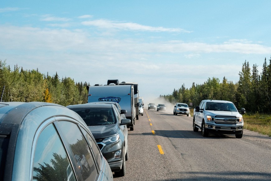 Cars pass a line of vehicles waiting for fuel, after an evacuation order was declared due to the proximity of a wildfire in Yellowknife, in Fort Providence, Northwest Territories, Canada August 17, 2023.  REUTERS/Pat Kane
