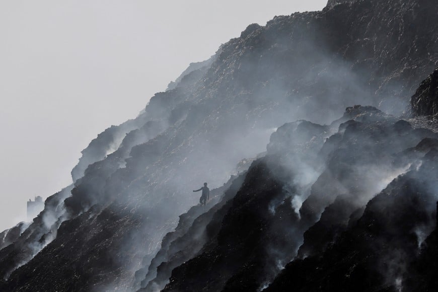 A waste collector climbs down while looking for recyclable materials as smoke billows from burning garbage at the Bhalswa landfill site on World Environment Day in New Delhi, India, June 5, 2022. REUTERS/Anushree Fadnavis/File Photo TPX IMAGES OF THE DAY SEARCH "GLOBAL POY" FOR THIS STORY. SEARCH "REUTERS POY" FOR ALL BEST OF 2022 PACKAGES.