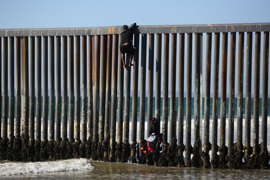 A migrant climbs the border fence to cross into the U.S. to request asylum, at Playas de Tijuana, in Tijuana, Mexico October 2, 2023. REUTERS/Jorge Duenes