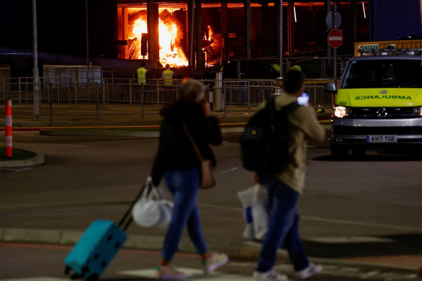 People leave as emergency services respond to a fire in Terminal Car Park 2 at London Luton airport in Luton, Britain, October 11, 2023.  REUTERS/Peter Cziborra