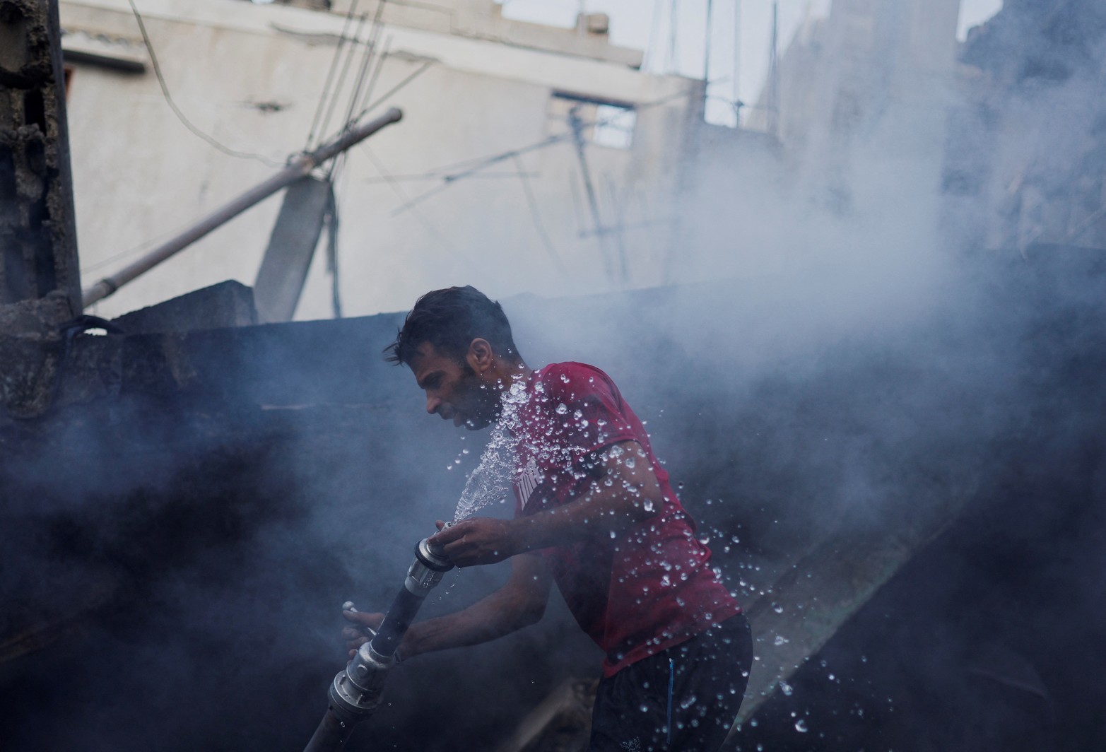 Un palestino usa una manguera de agua mientras busca bajo los escombros después de los ataques israelíes, en medio del conflicto en curso entre Israel y el grupo islamista palestino Hamas, en Khan Younis, en el sur de la Franja de Gaza.