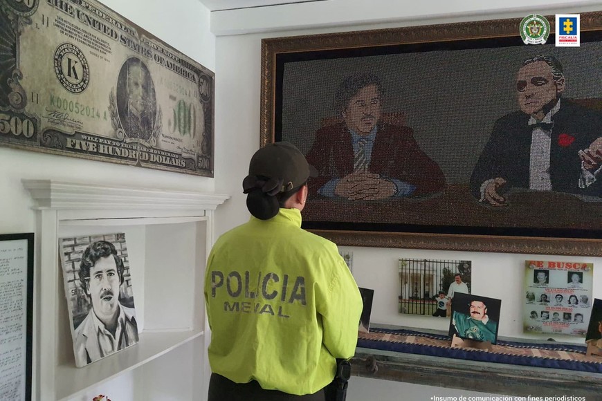 A police officer stands in front of a framed picture of late drug kingpin Pablo Escobar with "The Godfather" movie character Don Vito Corleone, at a property seized by the Colombian Prosecutor's office, in Medellin, Colombia, in this handout distributed to Reuters on October 20, 2023. Colombian Prosecutor's Office/Handout via REUTERS THIS IMAGE HAS BEEN SUPPLIED BY A THIRD PARTY. NO RESALES. NO ARCHIVES. WATERMARK FROM SOURCE