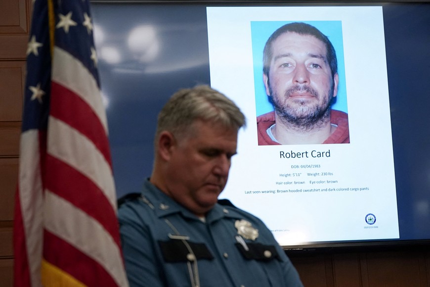 A police officer stands next to a screen displaying the picture of the suspected shooter, during a press conference following the deadly mass shooting, at City Hall in Lewiston, Maine, U.S. October 27, 2023. REUTERS/Kevin Lamarque